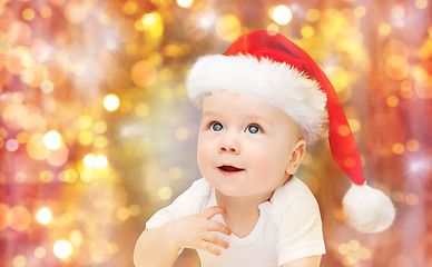 Image showing baby boy in christmas santa hat over blue lights