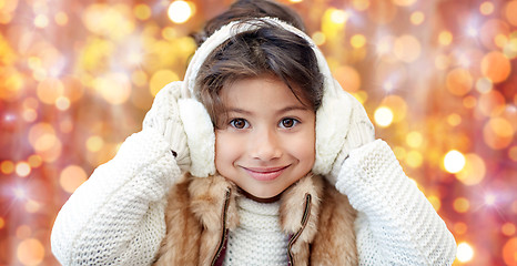 Image showing happy little girl in earmuffs over holidays lights