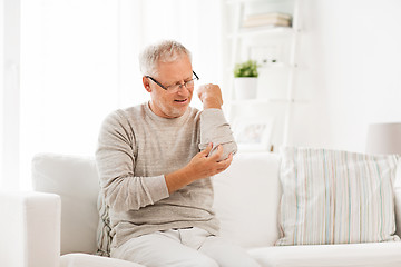 Image showing unhappy senior man suffering elbow pain at home