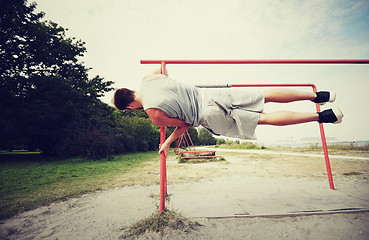 Image showing young man exercising on parallel bars outdoors