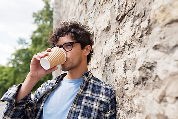 Image showing man in eyeglasses drinking coffee over street wall