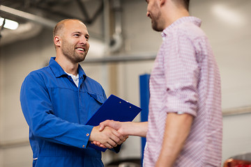 Image showing auto mechanic and man shaking hands at car shop