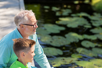 Image showing grandfather and grandson sitting on river berth