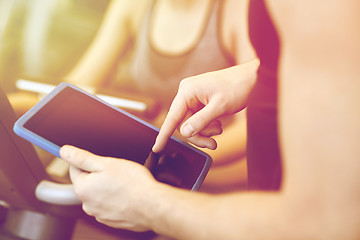 Image showing close up of trainer hands with tablet pc in gym