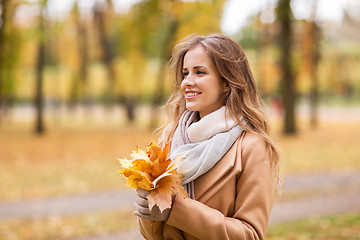 Image showing beautiful woman with maple leaves in autumn park