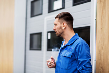 Image showing auto mechanic smoking cigarette at car workshop