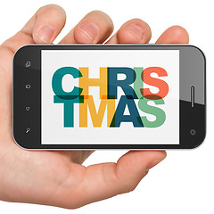 Image showing Holiday concept: Hand Holding Smartphone with Christmas on  display