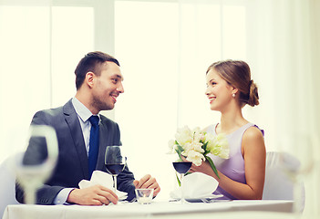 Image showing smiling man giving flower bouquet at restaurant