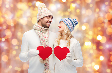 Image showing smiling couple in winter clothes with red hearts