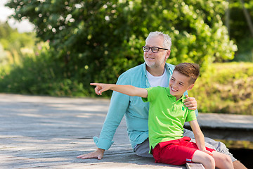 Image showing grandfather and grandson sitting on river berth