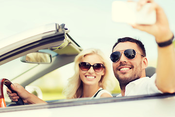 Image showing happy couple in car taking selfie with smartphone