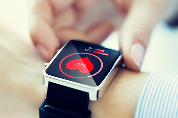 Image showing close up of hands with heart icon on smartwatch