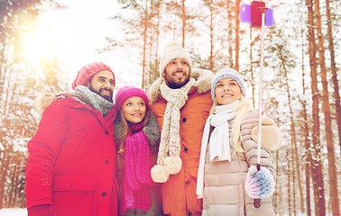 Image showing smiling friends with smartphone in winter forest