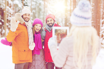 Image showing smiling friends with tablet pc in winter forest