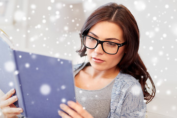 Image showing young woman in glasses reading book at home