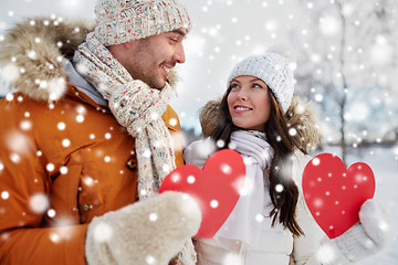 Image showing happy couple with red hearts over winter landscape