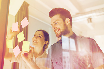 Image showing happy creative team writing on stickers at office