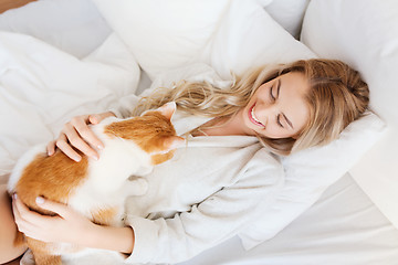 Image showing happy young woman with cat in bed at home