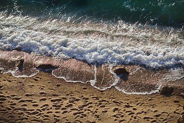 Image showing Waves lapping on the sandy beach and footprints