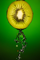 Image showing Ripe kiwifruit with drops of water isolated on green background