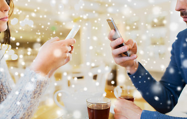 Image showing close up of couple with smartphones at cafe