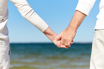 Image showing close up of senior couple holding hands on beach