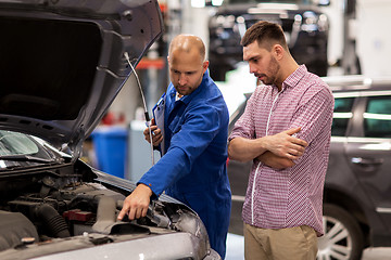 Image showing auto mechanic with clipboard and man at car shop