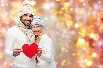 Image showing smiling couple in winter clothes with red hearts