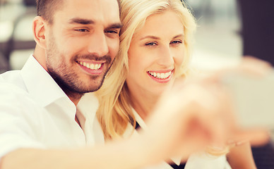 Image showing happy couple taking selfie with smatphone outdoors