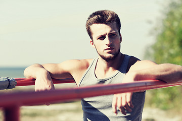 Image showing young man exercising on parallel bars outdoors