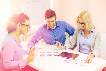 Image showing smiling team with table pc and papers working