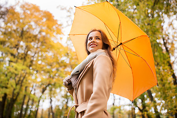 Image showing happy woman with umbrella walking in autumn park