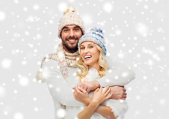 Image showing smiling couple in winter clothes hugging over snow