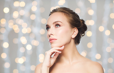 Image showing beautiful woman touching her face over lights