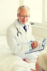 Image showing senior woman and doctor with clipboard at hospital