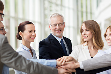 Image showing business people putting hands on top in office