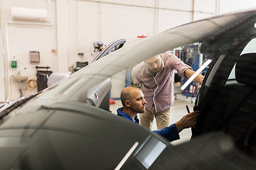 Image showing mechanic and man checking seat belt at car shop