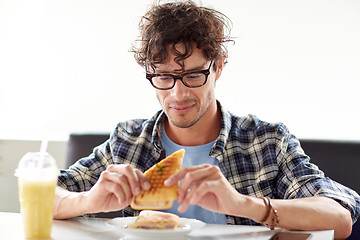 Image showing happy man eating sandwich at cafe for lunch