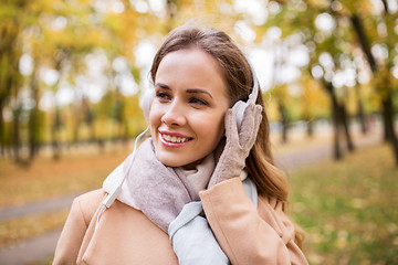 Image showing woman in headphones listening music at autumn park