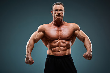 Image showing torso of attractive male body builder on gray background.