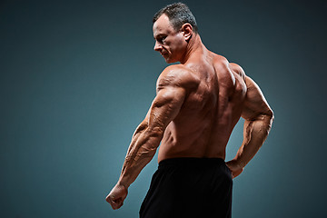 Image showing torso of attractive male body builder on gray background.