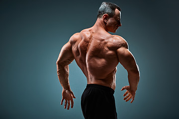 Image showing torso of attractive male body builder on gray background.