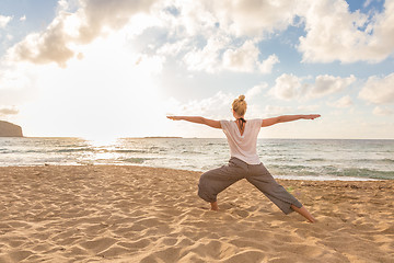 Image showing Woman practicing yoga on sea beach at sunset.