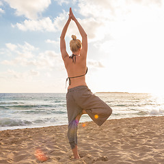 Image showing Woman practicing yoga on sea beach at sunset.