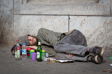 Image showing Homeless young alcohol addict lying drunk on street sidewalk in Berlin.