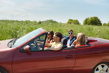 Image showing happy friends driving in cabriolet car and talking