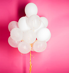 Image showing close up of white helium balloons over pink