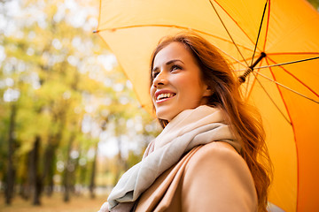 Image showing happy woman with umbrella walking in autumn park