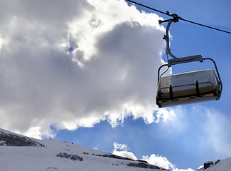 Image showing Chair-lift in ski resort and blue sky with sunlight clouds at su