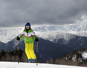 Image showing Young skier jumping with ski poles in sun mountains and cloudy g